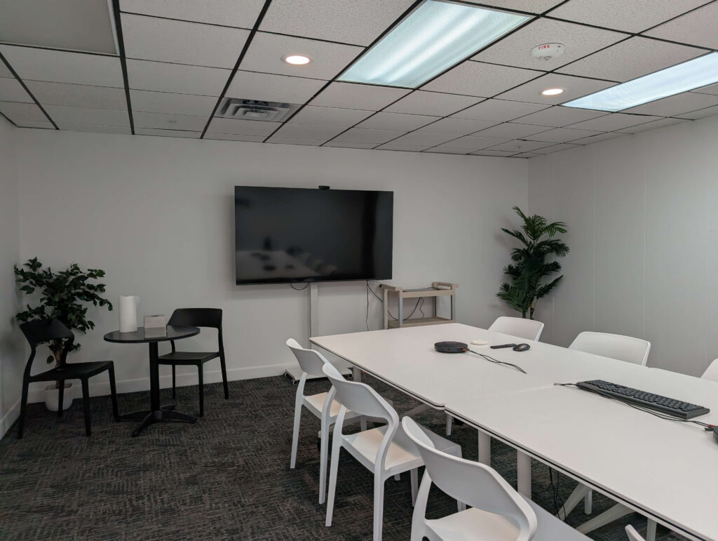 long table with chairs in front of a TV monitor